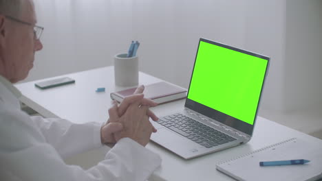 Ein-Männlicher-Arzt-Berät-Online-Und-Schaut-Sich-Den-Grünen-Bildschirm-Eines-Laptops-Im-Büro-Der-Chroma-Key-Technologie-Der-Klinik-An